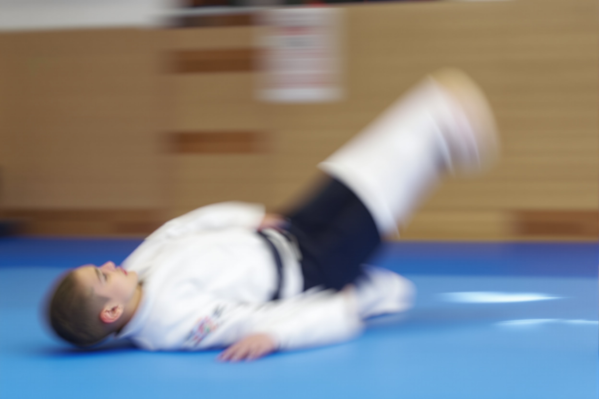 A beginner mid-roll on the mat, practicing a safe forward breakfall
